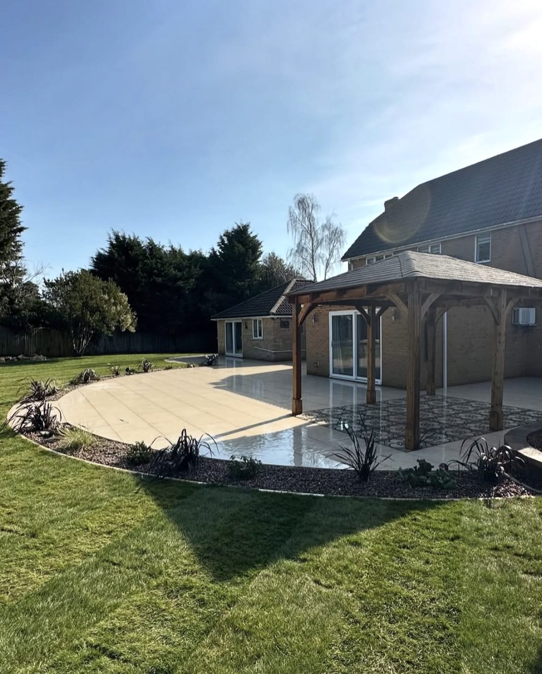 Large curved cream patio with an oak gazebo and patterned tile inset
