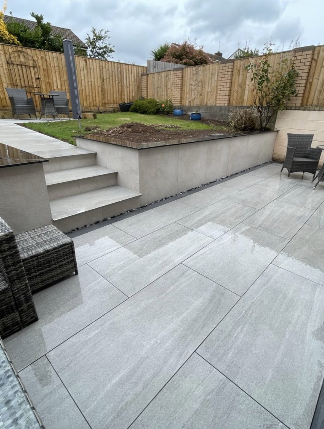 Split-level porcelain patio with a rendered retaining wall built by GreenForge