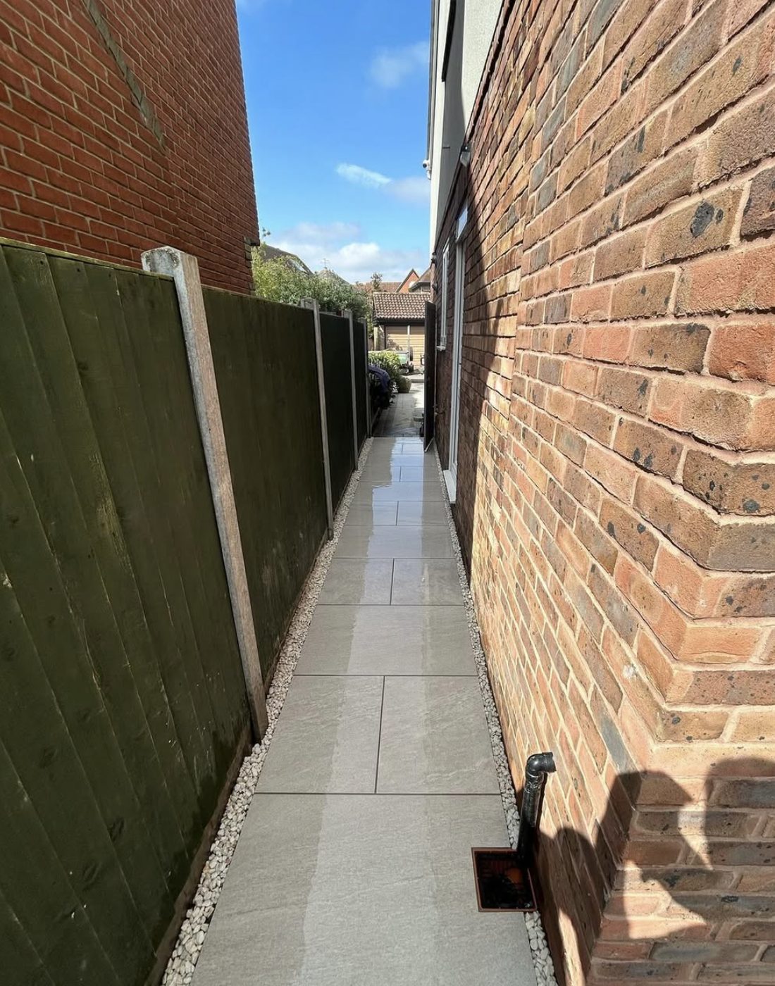 Narrow porcelain path along the side of a house with gravel margins